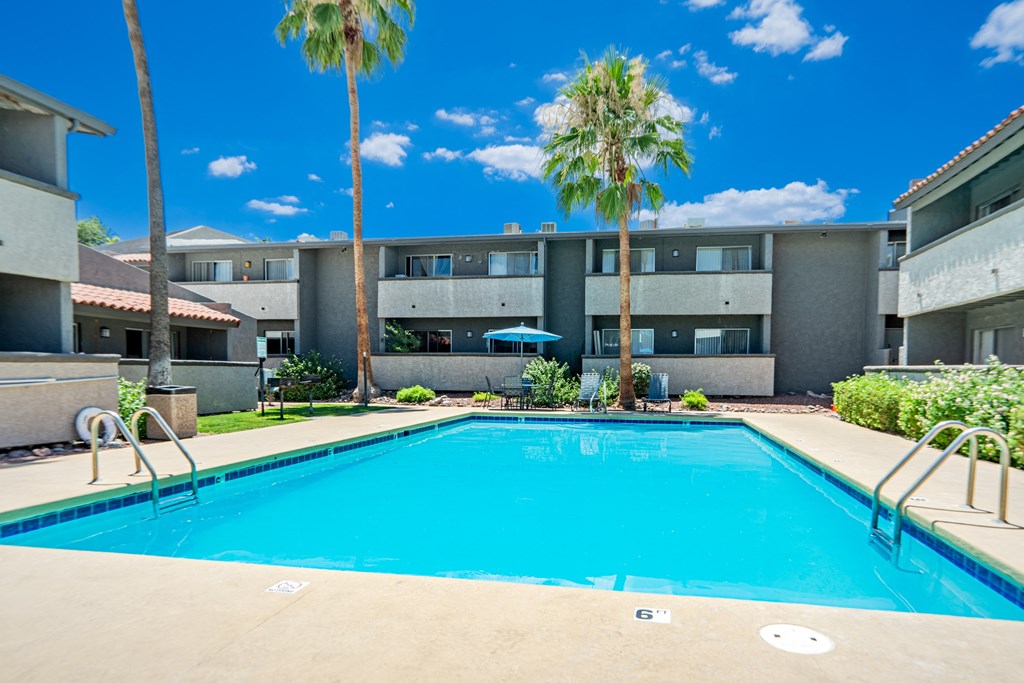 a swimming pool in front of a building with palm trees
