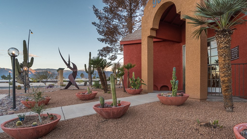 Front of building with large clay pots with cacti and view of mountains
