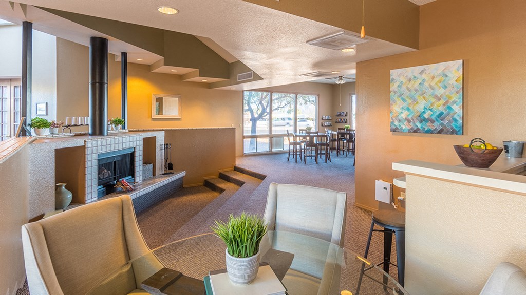 Clubhouse with fireplace and seating near large room with windows for walls.