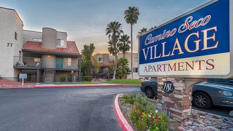 Blue and white lit sign on top of bricks, buildings in background