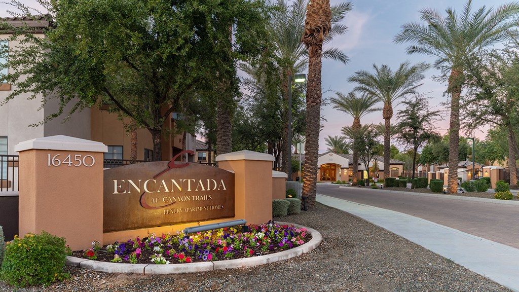 a community sign with flowers and trees in the background