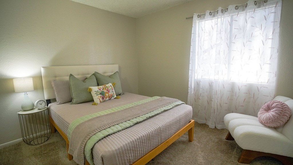 A bedroom with a bed, a chair, and a lamp.