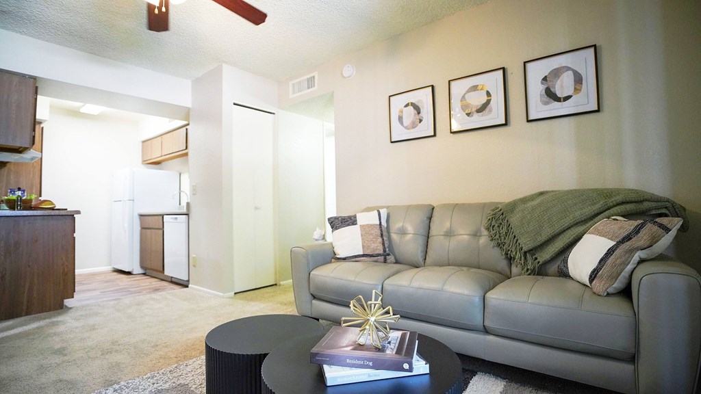 A living room with a grey couch, a coffee table, and a ceiling fan.