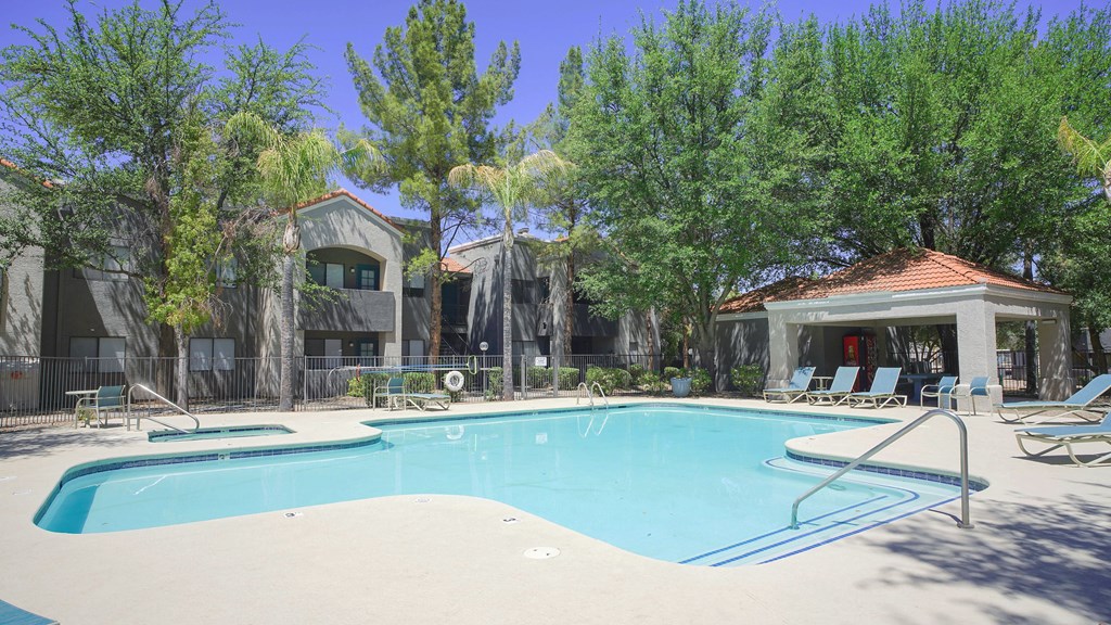 A swimming pool surrounded by trees and a building in the background.