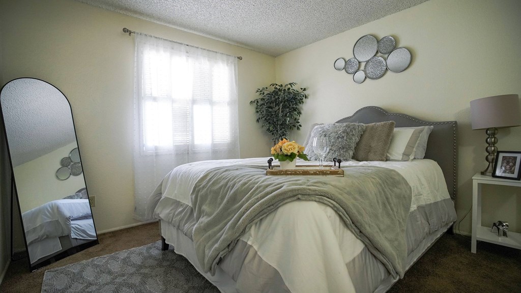 A bedroom with a large bed and a mirror on the wall.