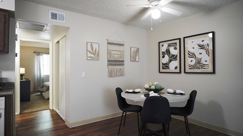 A dining room with a table set for two and a painting on the wall.