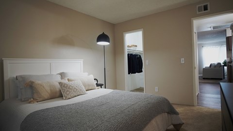 A bedroom with a large bed and a lamp.