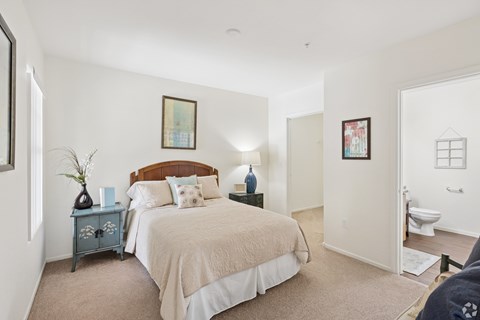 A bedroom with a bed, nightstand, and a painting on the wall.