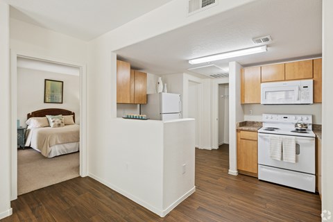 A white kitchen with wooden cabinets and a white stove top oven.