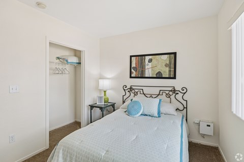 A bedroom with a bed, nightstand, and a painting on the wall.
