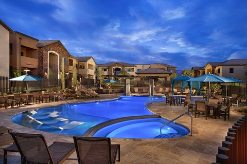 A swimming pool surrounded by chairs and umbrellas in a residential area.