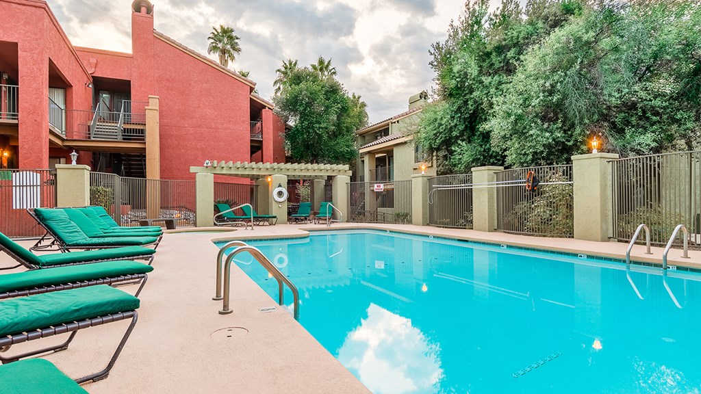 a resort style swimming pool with ramada in background