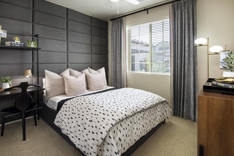a bedroom with a bed and a desk and a window