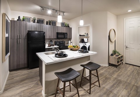 a kitchen with a large island and a black refrigerator