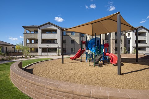 a playground with a tent and slides in front of an apartment complex