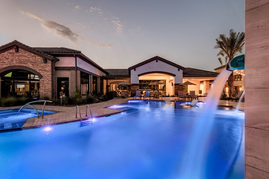 a swimming pool with blue lights in front of a resort
