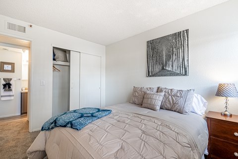A bedroom with a large bed and a painting on the wall.