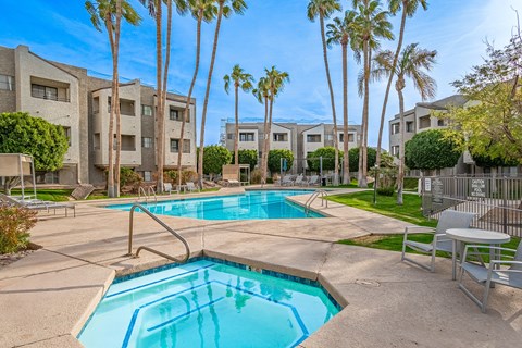 A swimming pool surrounded by palm trees and apartment buildings.