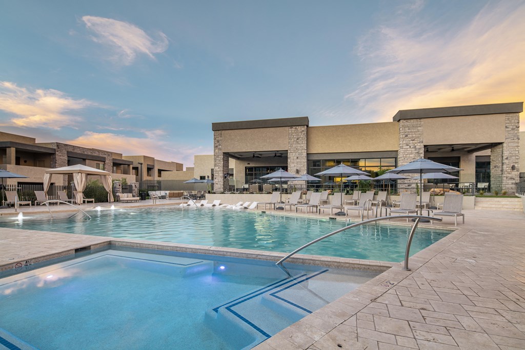 a resort style pool with lounge chairs and umbrellas