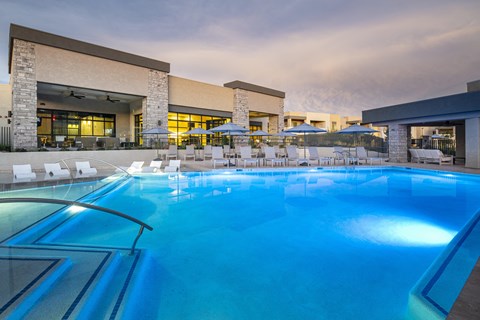 a large swimming pool with lounge chairs and umbrellas