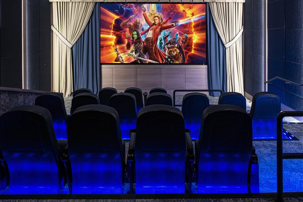 a theater with blue chairs and a large movie screen on the wall