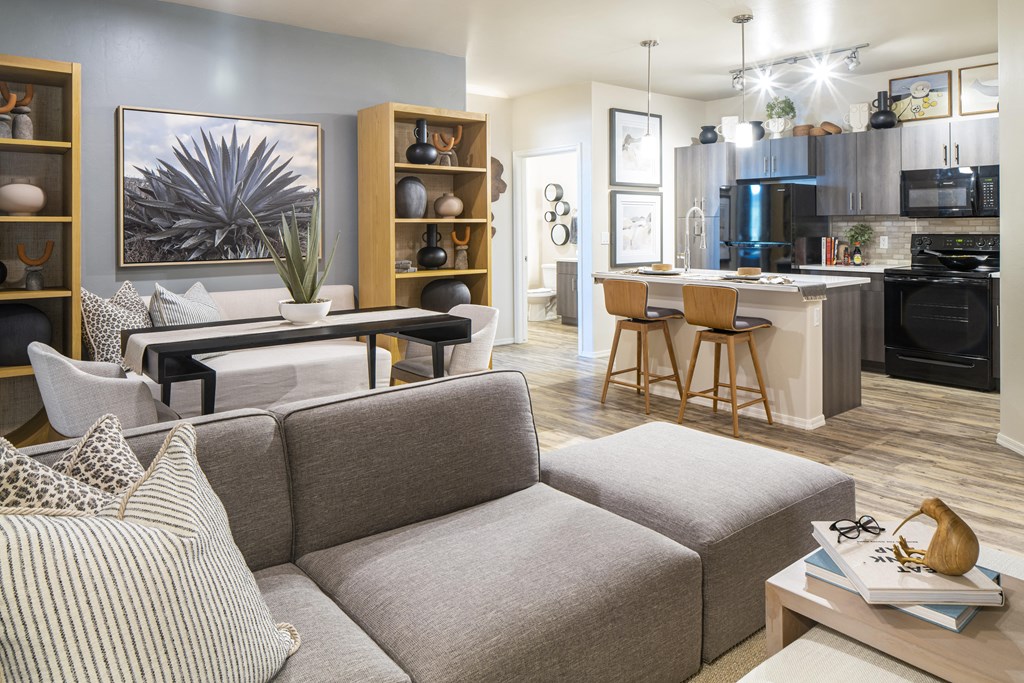 a living room and kitchen area with a gray couch and a black dining table