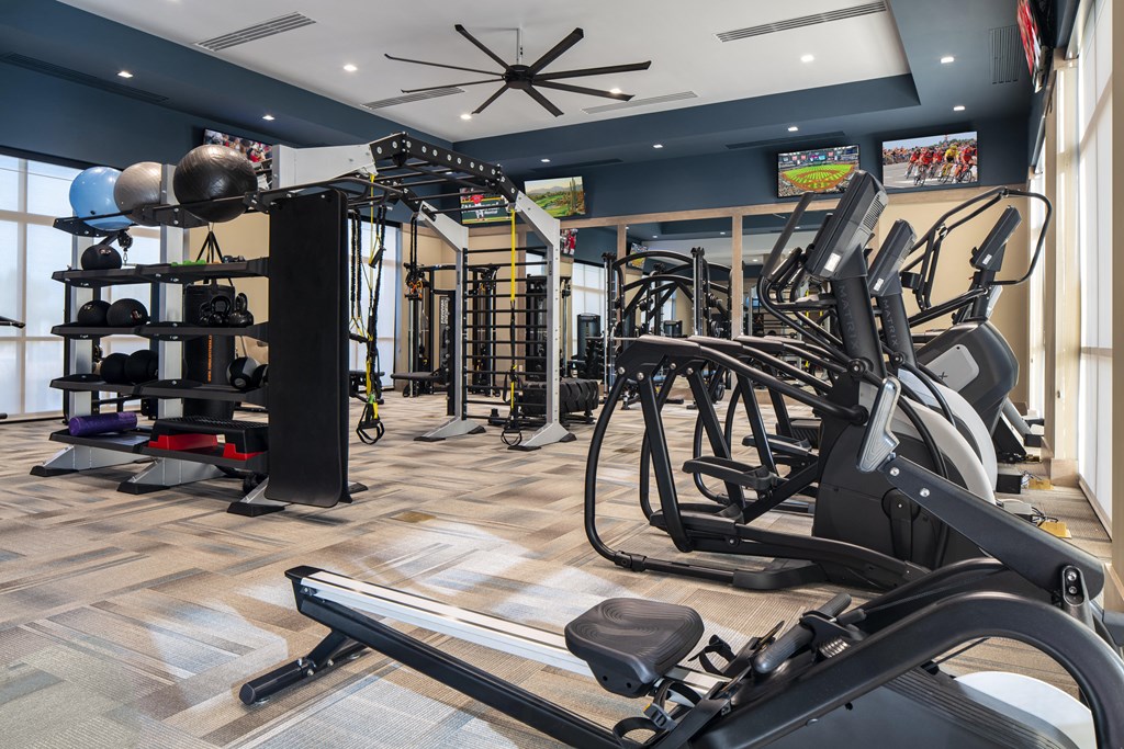 a spacious fitness room with cardio equipment and weights