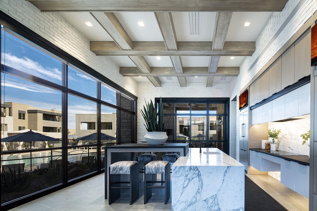 a kitchen with a large island with a marble countertop and a breakfast bar with stools