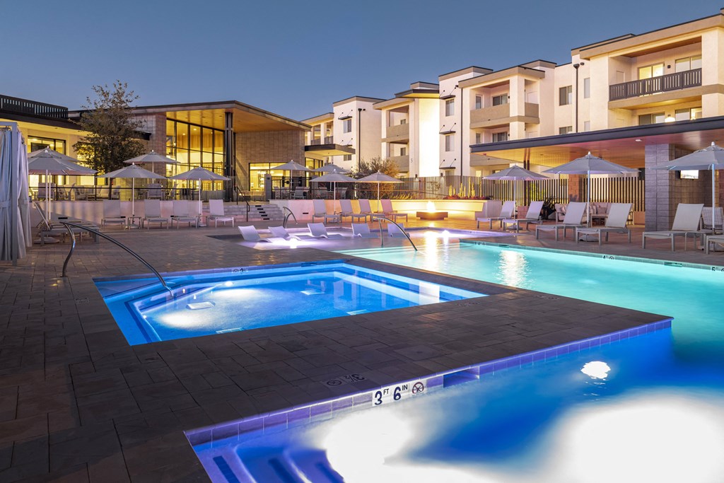 a swimming pool at night at an apartment complex with a hot tub