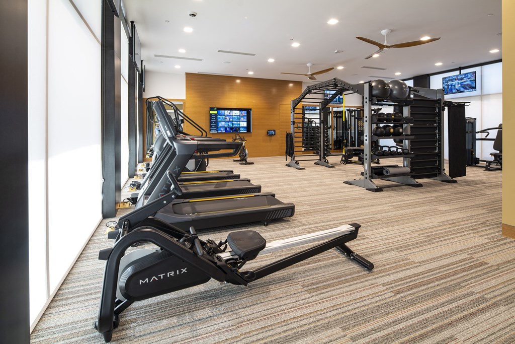 a gym with treadmills and other exercise equipment in a room with a window