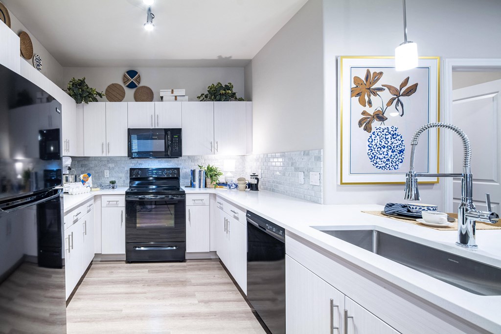a large kitchen with white cabinets and black appliances