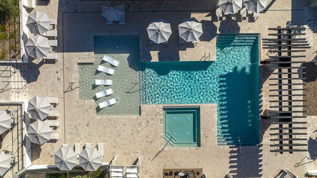 an aerial view of a pool and umbrellas on the side of a building