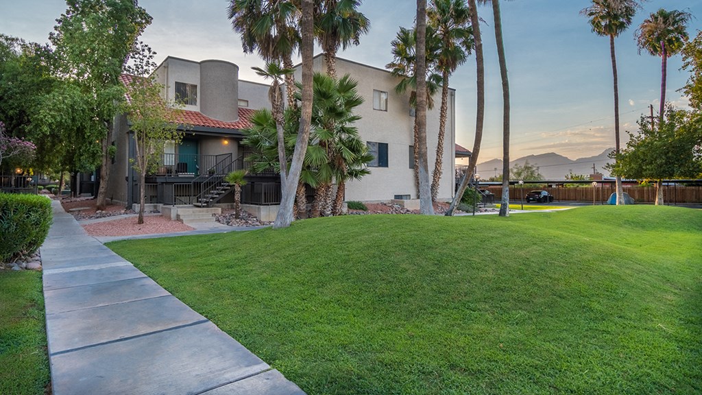 large grass area in front of apartment with palm tress