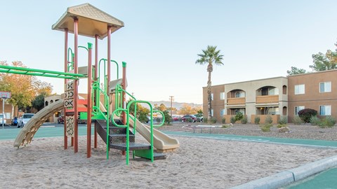 A playground with a green slide and a sandbox.