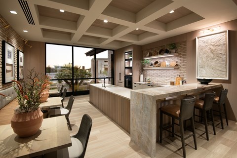A modern kitchen with a bar area and a dining table with chairs.
