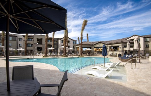 A pool area with a table and chairs and umbrellas.