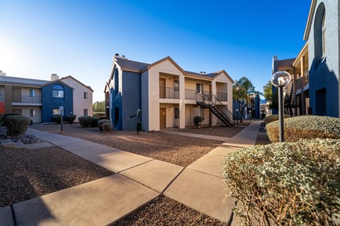 A sunny day in a residential area with apartment buildings and a sidewalk.