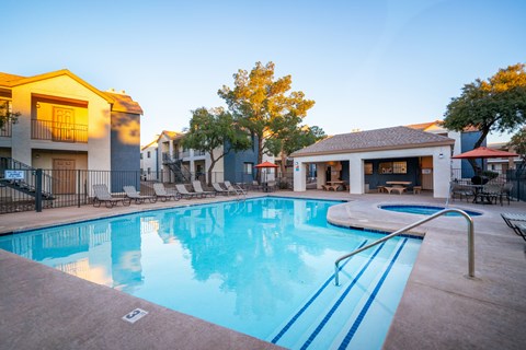 A swimming pool surrounded by a fence and chairs.