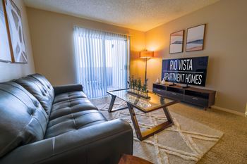A living room with a black leather sofa and a coffee table with a plant on it.