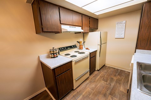 A kitchen with a stove, refrigerator, and wooden cabinets.