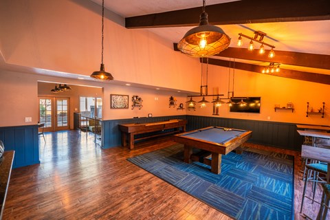 A room with a pool table and a bar area.