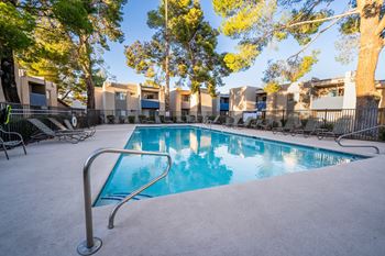A pool surrounded by trees and chairs in a residential area.