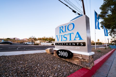 A sign for Rio Vista Apartments is displayed in front of a parking lot.