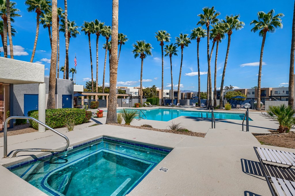 a swimming pool with palm trees in front of a building with a pool and chairs