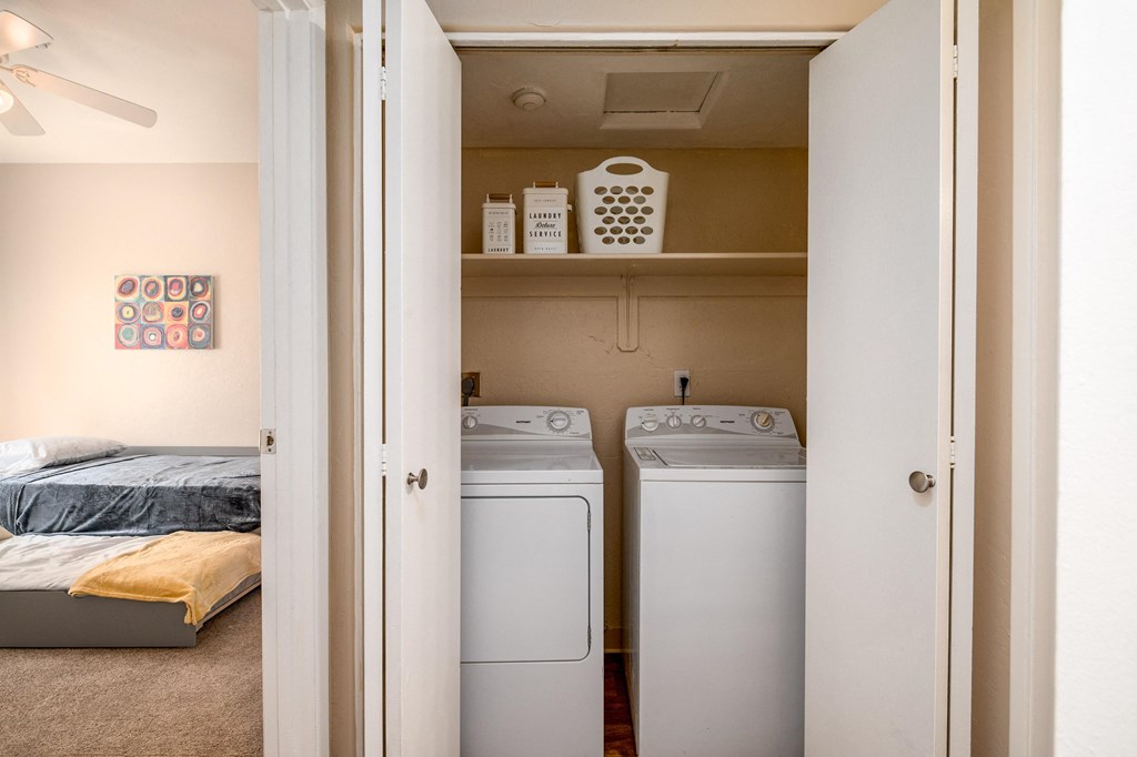 a bedroom with a washer and dryer and a closet with a bed