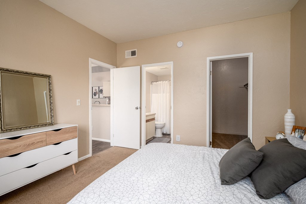 a bedroom with a large bed and a mirror and a bathroom