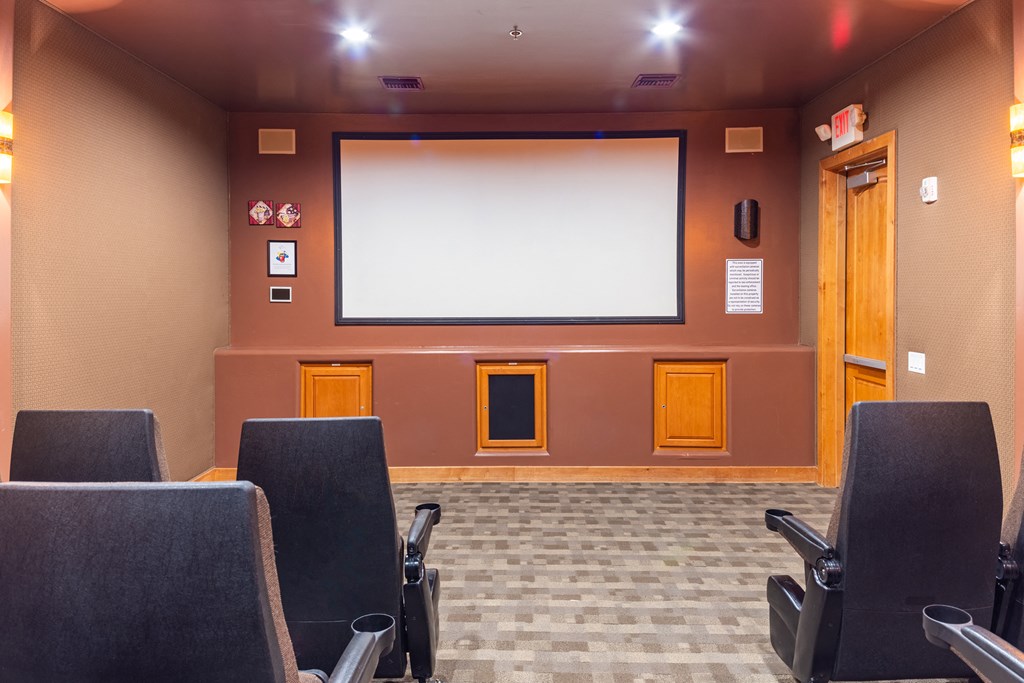 a room with chairs and a large screen on the wall