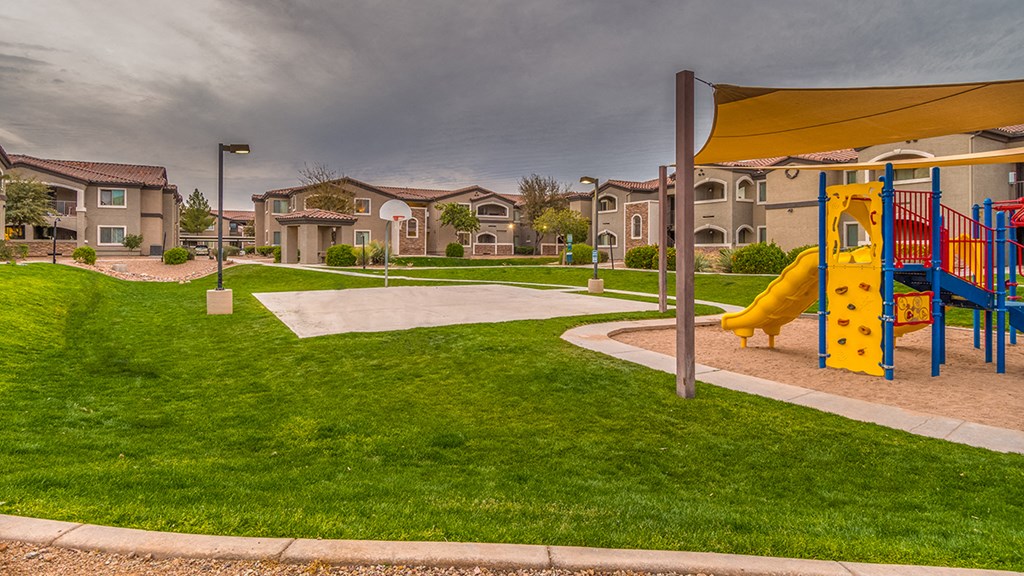 Desert Sands playground and basketball court surrounded by green grass.