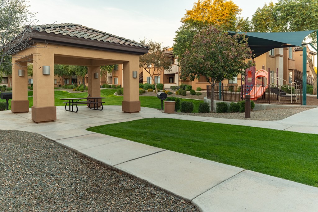 a park with a playground and gazebo at the whispering winds apartments in pearland