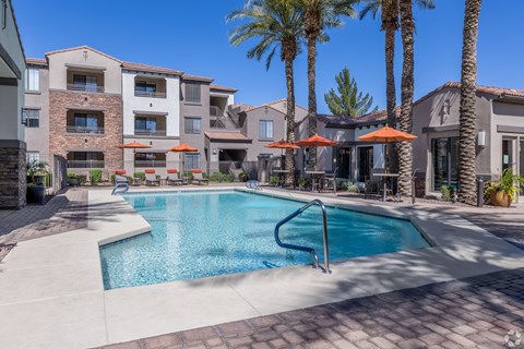 A swimming pool surrounded by palm trees and apartment buildings.